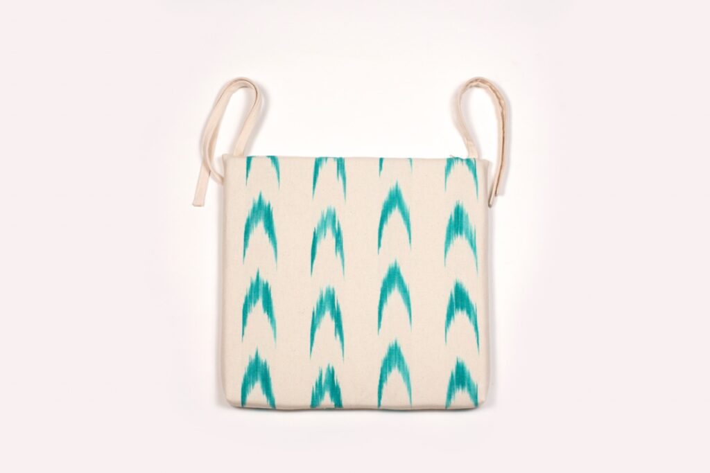 Cojín para silla con lazos, diseño mallorquín en verde turquesa sobre fondo blanco de Teixits Vicens