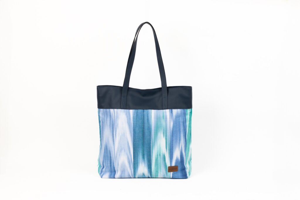 Bolso tote grande con asas negras y diseño ikat en tonos azules y verdes sobre fondo blanco
