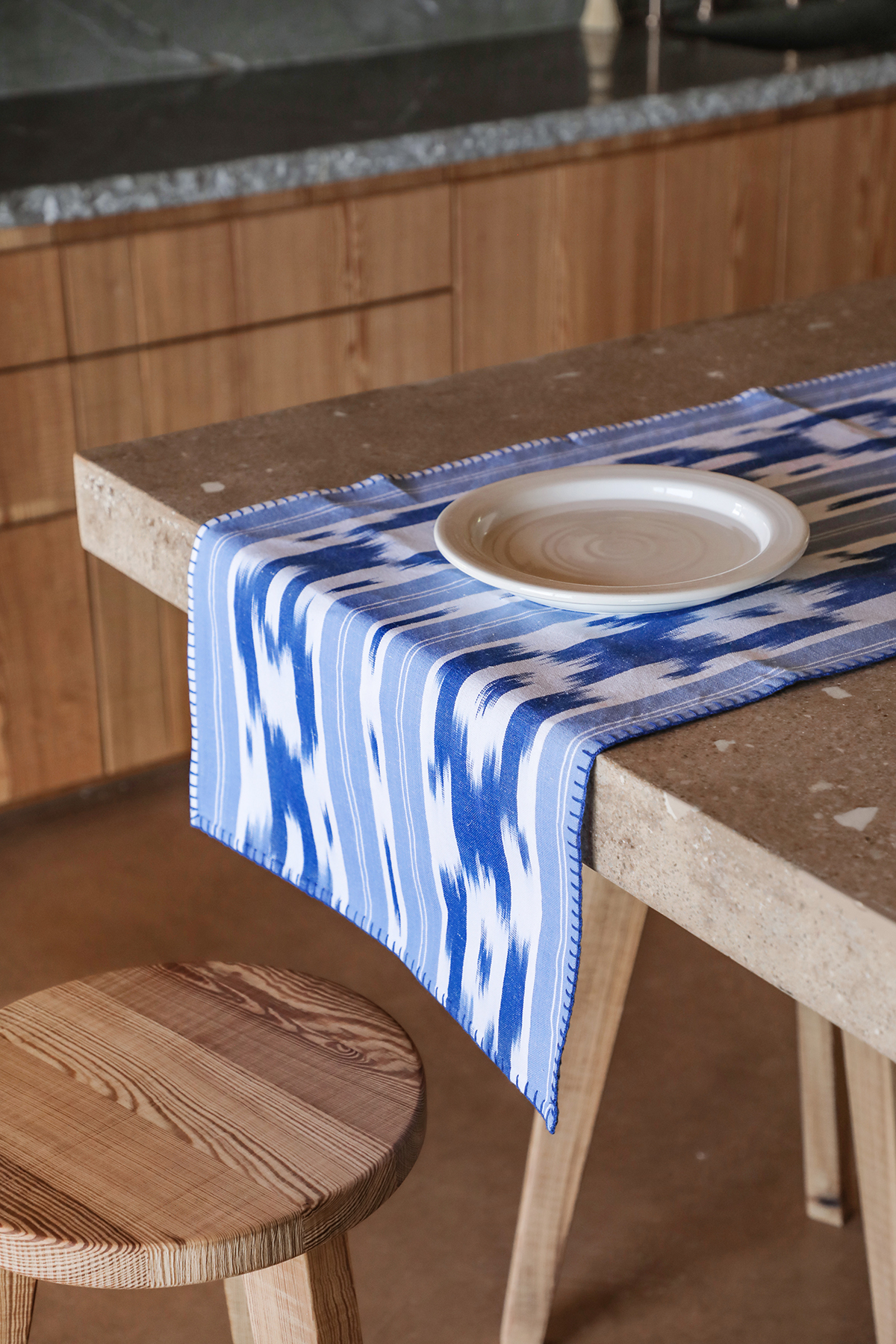 Camino de mesa blanco con diseño ikat azul colocado en mesa rústica